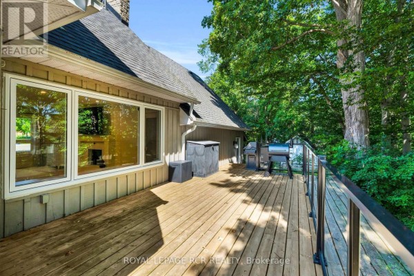 Wooden deck with grill and glass railing, surrounded by trees - 163 Confederation Street Halton Hills