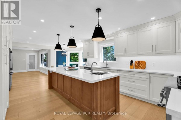 Modern kitchen with island, white cabinets, quartz counters, and pendant lights - 163 Confederation Street Halton Hills