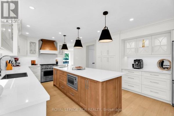 Modern kitchen with island, stainless steel appliances, and copper hood - 163 Confederation Street Halton Hills