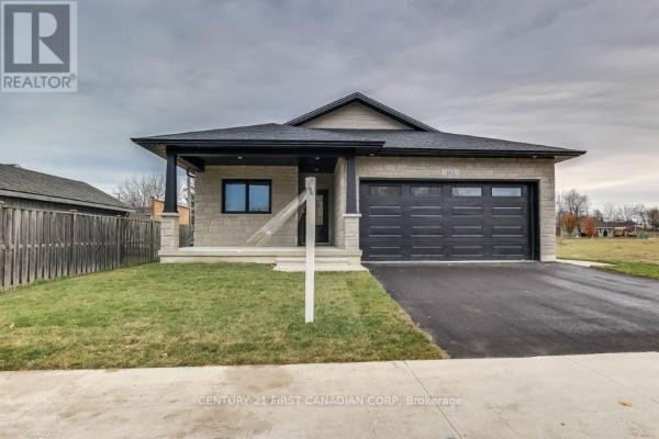 Front exterior view of a beige brick bungalow with a covered front porch and driveway. - 163 Elgin Avenue E, Goderich)