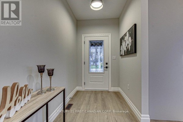 Interior foyer with light grey walls, wood-look laminate flooring, and a glass-panelled front door. - 163 Elgin Avenue E, Goderich)