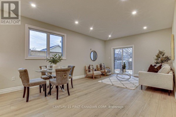 Open concept living and dining area with light grey walls, wood-look floors, and a sliding glass door. - 163 Elgin Avenue E, Goderich)