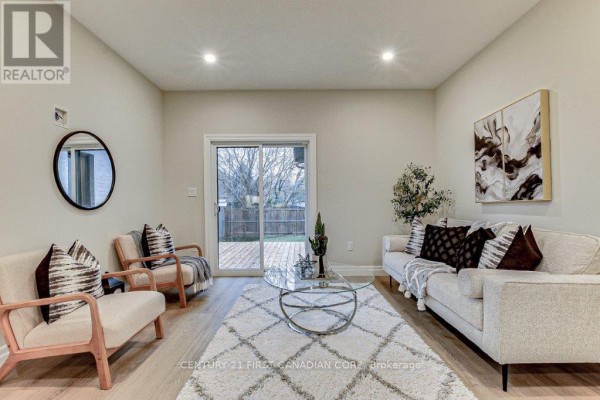 Living room with light grey walls, a white sofa, two chairs, and a large sliding glass door to the backyard. - 163 Elgin Avenue E, Goderich)