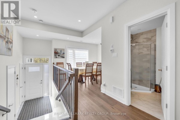 Interior entryway with white door, staircase, and view into a dining area and bathroom. - 163 Longpre Street, Ottawa