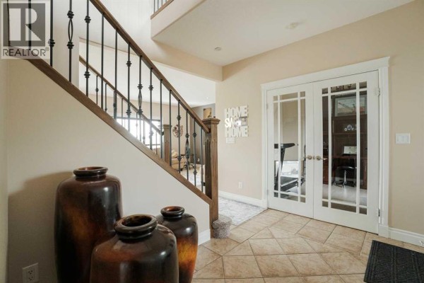 Foyer with beige walls, French doors leading to an office, and decorative vases. - 163 Rattlepan Creek Crescent, Fort Mcmurray