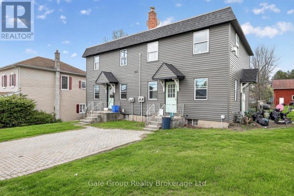 Three-quarter exterior view of the grey duplex with adjacent properties and green lawn. - 163 Thames Street N, Ingersoll