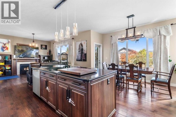 Open concept living and dining area with hardwood floors, a fireplace, and a large island. - 163 Wiley Crescent, Red Deer