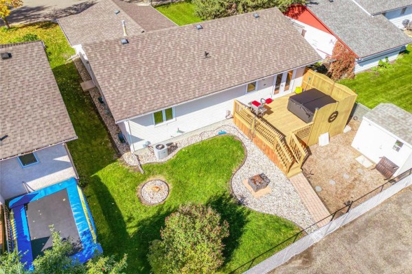 Aerial view of the backyard with a wooden deck, hot tub, fire pit, and trampoline. - 1631 22nd Street, Brandon