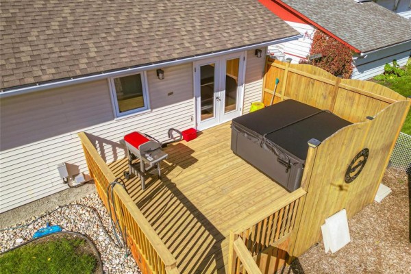 Close-up aerial view of the wooden deck featuring a hot tub, barbecue, and double doors. - 1631 22nd Street, Brandon