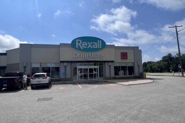 The Rexall Drugstore features a grey facade with a large blue oval sign above the entrance. - 1631 St Mary's Road, Winnipeg