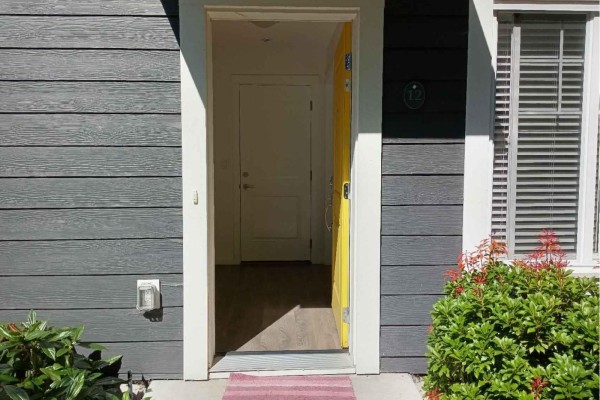 Front door with a bright yellow door and grey siding. - 16337 15 Avenue, Surrey