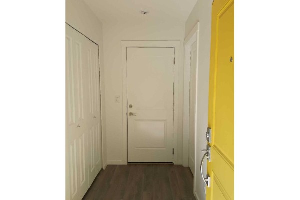 Interior entryway with white double doors, a yellow door, and wood flooring. - 16337 15 Avenue, Surrey