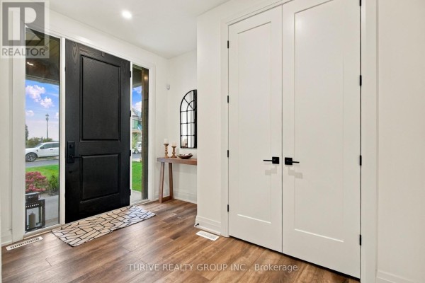 Foyer with a black front door, wood-look flooring, a console table, and double white doors. - 1635 Upper West Avenue, London South