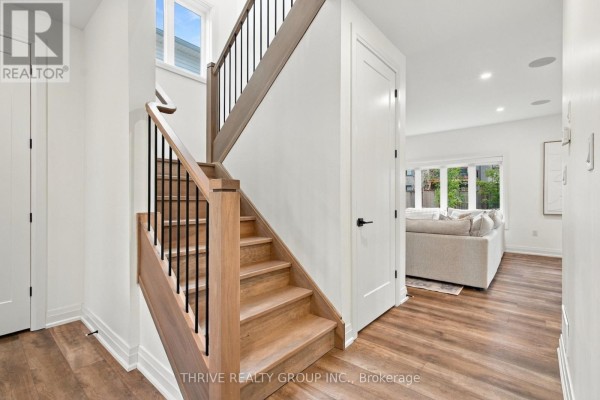 Interior view of a wooden staircase with black spindles and a glimpse of a living room. - 1635 Upper West Avenue, London South