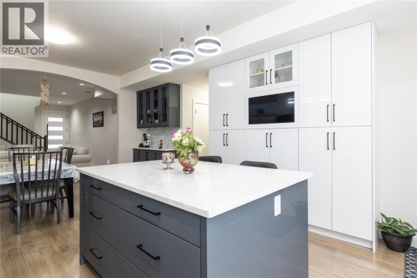 Kitchen island and dining area with a view into a staircase and living room. - 1636 Roberta Rd S, Nanaimo