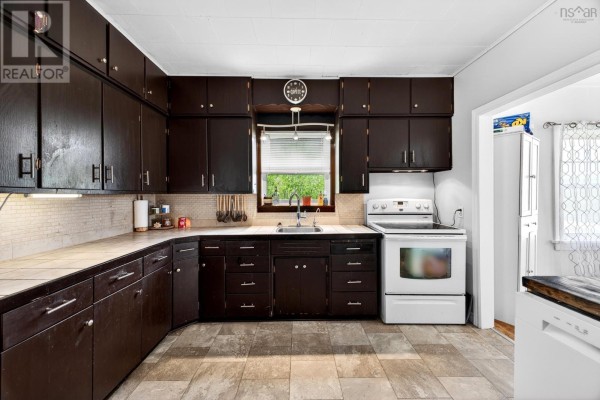 Kitchen with dark wood cabinets, a white stove and refrigerator, and a sink under a window. - 16364 Highway 2, Springhill Junction