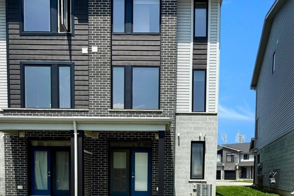 Close-up of townhouse exterior with multiple windows and brick detailing. - 164 - 177 Edgevalley Road, London East