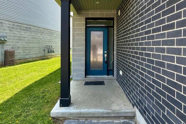 Front entrance of a townhouse with a teal door and concrete porch. - 164 - 177 Edgevalley Road, London East