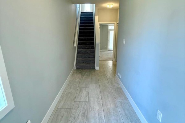 Interior hallway with light gray walls, tile floor, and carpeted stairs. - 164 - 177 Edgevalley Road, London East