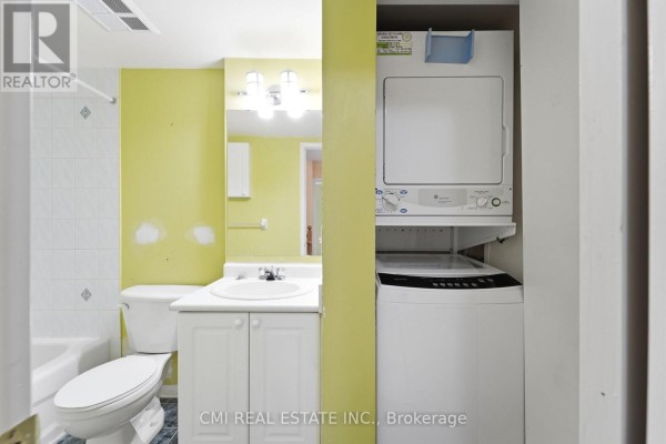 Bathroom with a bathtub, toilet, sink, vanity, and stacked white washer and dryer. - 164 - 760 Lawrence Avenue W, Toronto