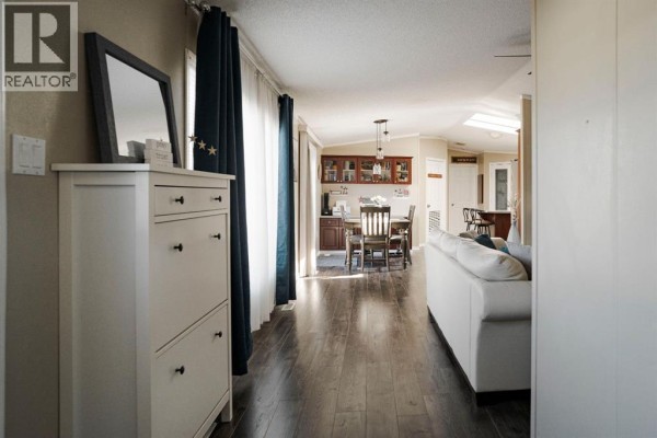 Hallway view towards dining and living areas with dark wood floors. - 164 Balsam Way, Fort Mcmurray
