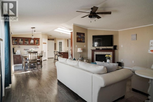 Living room with white sofa, fireplace, television, and open concept dining area. - 164 Balsam Way, Fort Mcmurray