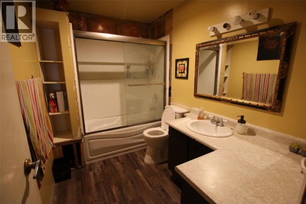 Bathroom with a bathtub, toilet, sink, vanity, and mirror. - 164 Bergeron Drive, Tumbler Ridge