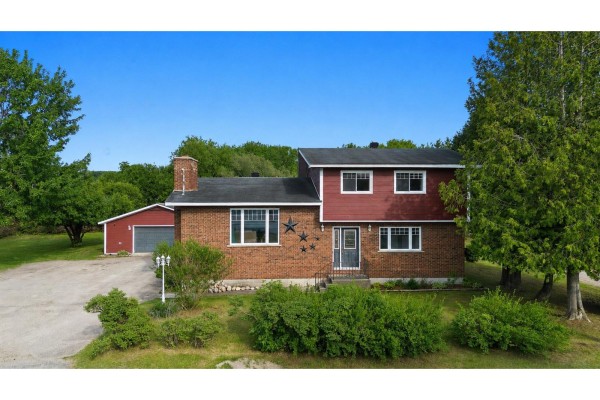 Exterior view of a two-story brick and red siding house with a garage. - 164 Ch. Fortin, Mansfield Et Pontefract
