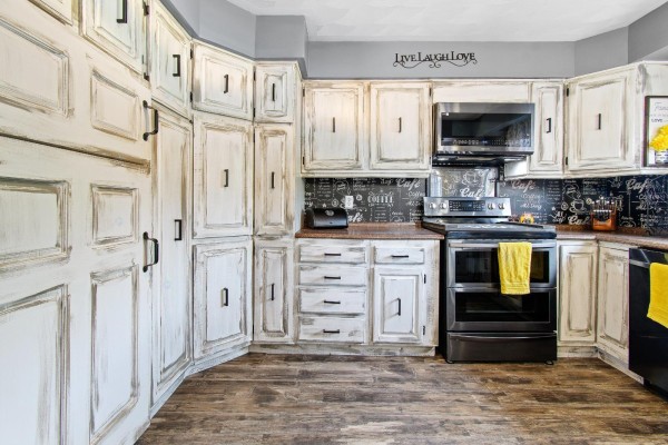 Kitchen with abundant white distressed cabinets, dark countertops, and stainless steel appliances. - 164 Ch. Fortin, Mansfield Et Pontefract
