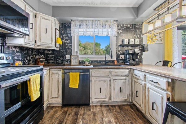 Kitchen island with seating, black sink, stainless steel dishwasher, and window view. - 164 Ch. Fortin, Mansfield Et Pontefract