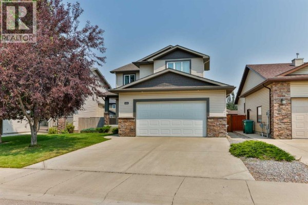 Front exterior of a two-story house with stone accents and a double garage door. - 164 Rivermill Landing W, Lethbridge