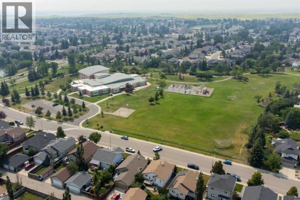 Aerial view of a suburban neighborhood with houses, a school, and a park. - 164 Rivermill Landing W, Lethbridge