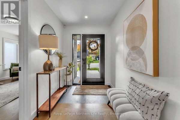 Interior hallway of a modern home with white walls, dark wood floors, a console table, bench, and artwork. - 164 Sugarbush Street, North Bay