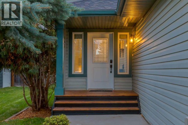 Front entryway of the house with a white door, sidelights, and wooden steps. - 164 Sunset Heights, Crossfield