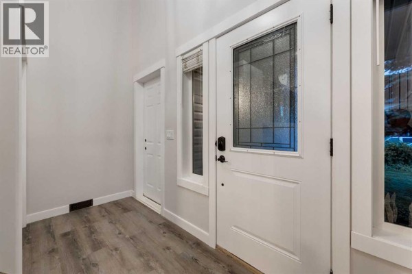 Interior view of the entranceway showing a white door with a glass insert and wood-look flooring. - 164 Sunset Heights, Crossfield