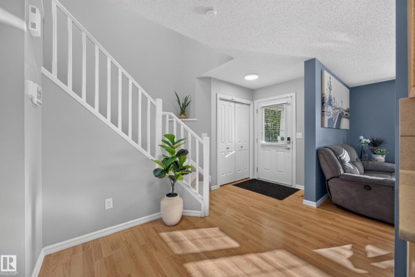View of the foyer, staircase, and a section of the living room with a blue wall. - 16408 59 St Nw, Edmonton