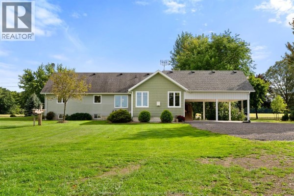 Side and rear exterior view of the house with green siding and a covered carport. - 1642 Road 2 West, Kingsville