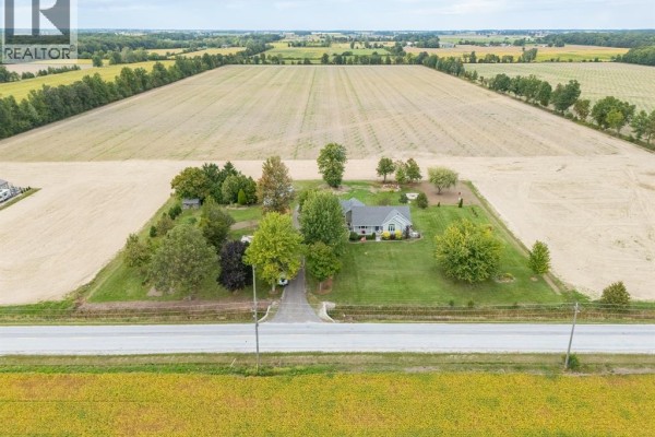Aerial view of the residential property surrounded by agricultural fields under a blue sky. - 1642 Road 2 West, Kingsville