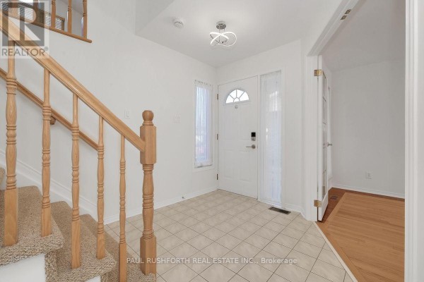 Foyer with a front door, tile floor, and carpeted staircase leading upstairs. - 1644 Toulouse Crescent, Ottawa
