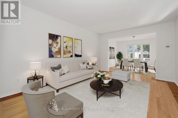 Living room with a beige sofa and armchairs, featuring a view into the dining room. - 1644 Toulouse Crescent, Ottawa