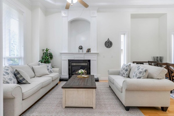 Living room with a gas fireplace, white mantelpiece, sofa, coffee table, and side table. - 16488 104a Avenue, Surrey