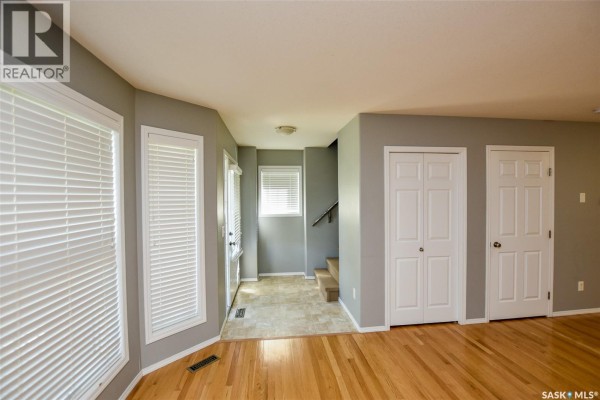 Bright living area with hardwood floors, large bay windows, and white doors. - 165 615 Stensrud Road, Saskatoon