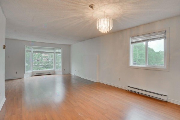 Spacious living room with wood floors, white walls, and large windows. - 165 Av. Des Jonquilles, #74, Gatineau