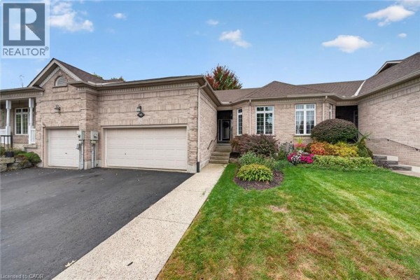 Exterior front view of a brick townhouse with an attached garage and landscaped front yard. - 165 Doon Mills Drive, Kitchener