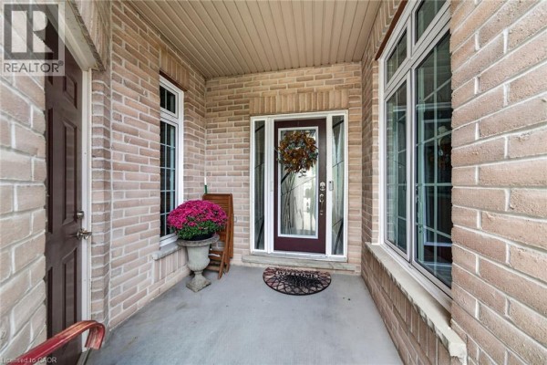 Front porch of a townhouse with a glass front door, large windows, and decorative planters. - 165 Doon Mills Drive, Kitchener