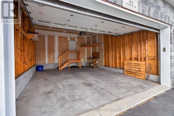 Interior of a two-car garage with a concrete floor, unfinished wood walls, and a wooden staircase. - 165 Islandview Drive, Loyalist