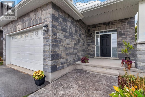 Exterior detail of the house, featuring grey stone veneer, a white garage door, and front entrance steps. - 165 Islandview Drive, Loyalist