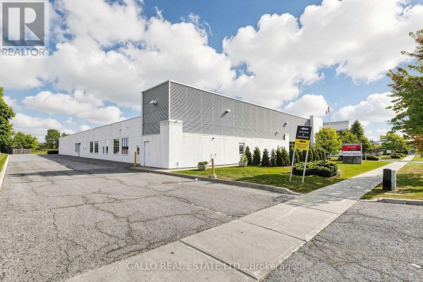 Rear exterior view of the commercial building with a parking lot and landscaping. - 165 Mostar Street, Whitchurch Stouffville
