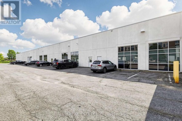 Long view of the white commercial building exterior with windows and a parking lot. - 165 Mostar Street, Whitchurch Stouffville