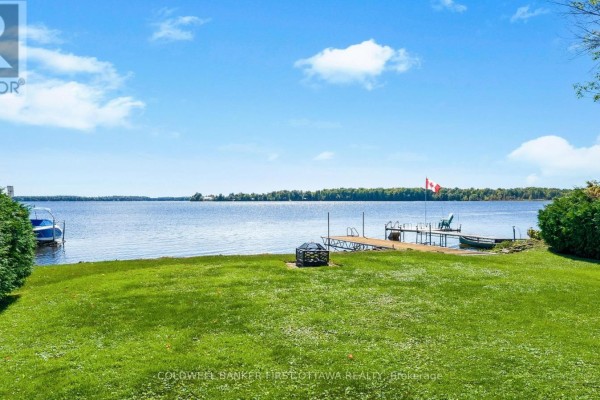 View of a lake with a dock, chairs, and a Canadian flag. - 165 Rideau Street, Drummond/north Elmsley